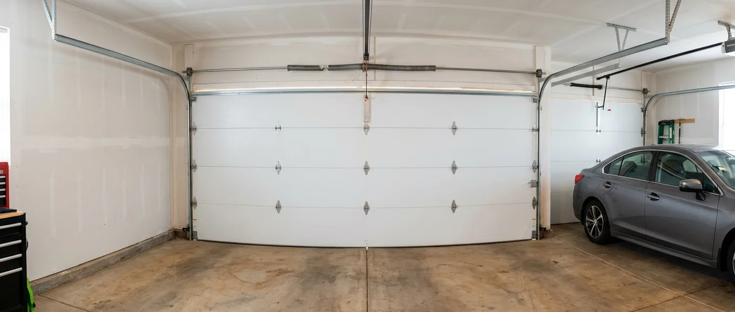 A garage door shut tight from the inside, a sedan parked beside it